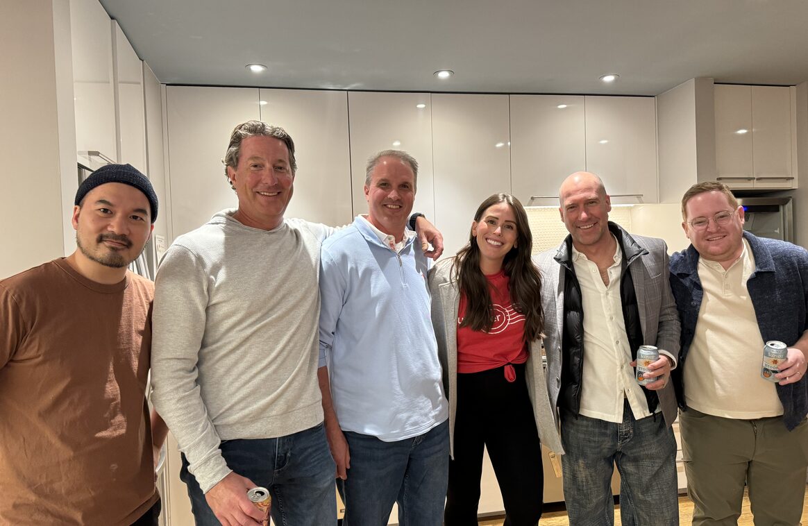 Six Updater colleagues gathered with drinks in an office kitchen