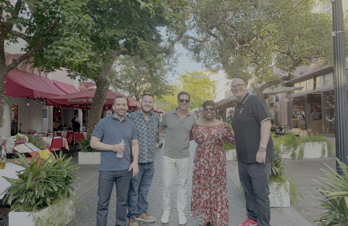Five Updater colleagues standing together on a tree-lined street at a team offsite