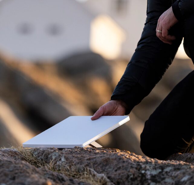 A person setting a Starlink Mini kit down on a rock outdoors