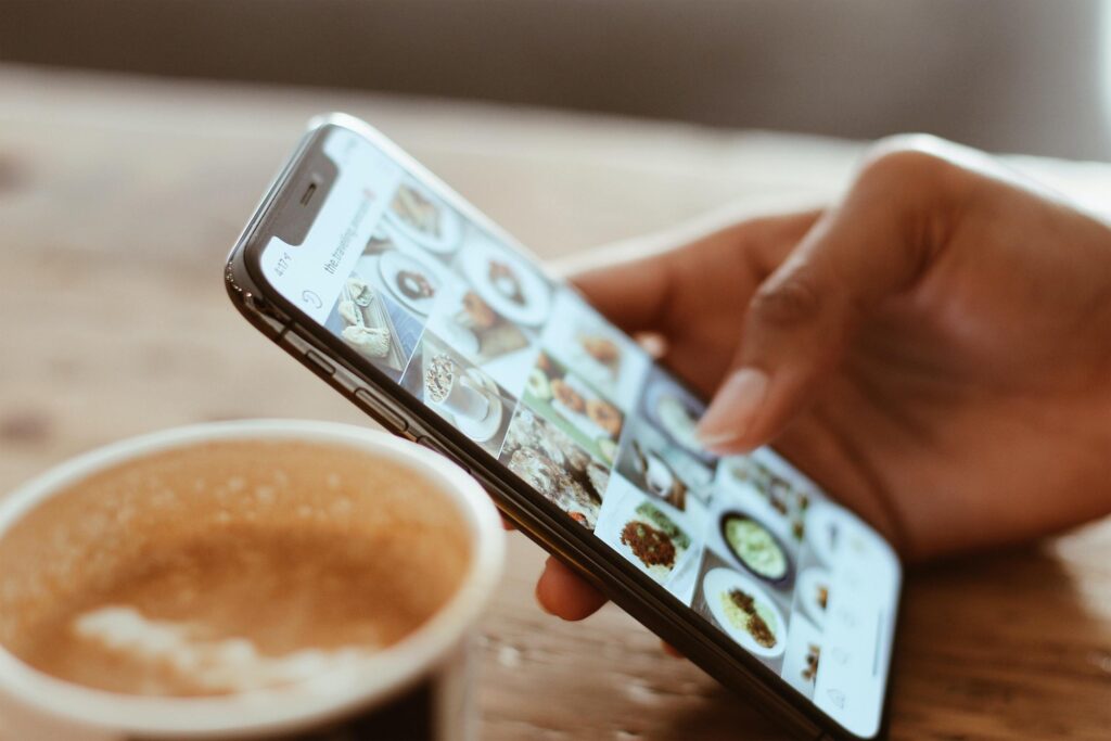 Hand on iphone next to cup of coffee